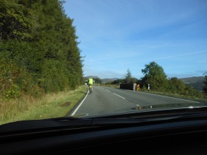 A cyclist in the middle of the A87—on a curve, with a bridge—on the Isle of Skye. Photo by Alexas Orcutt.